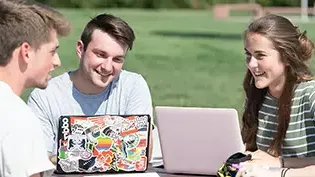 学生们在外面的桌子上用笔记本电脑学习.